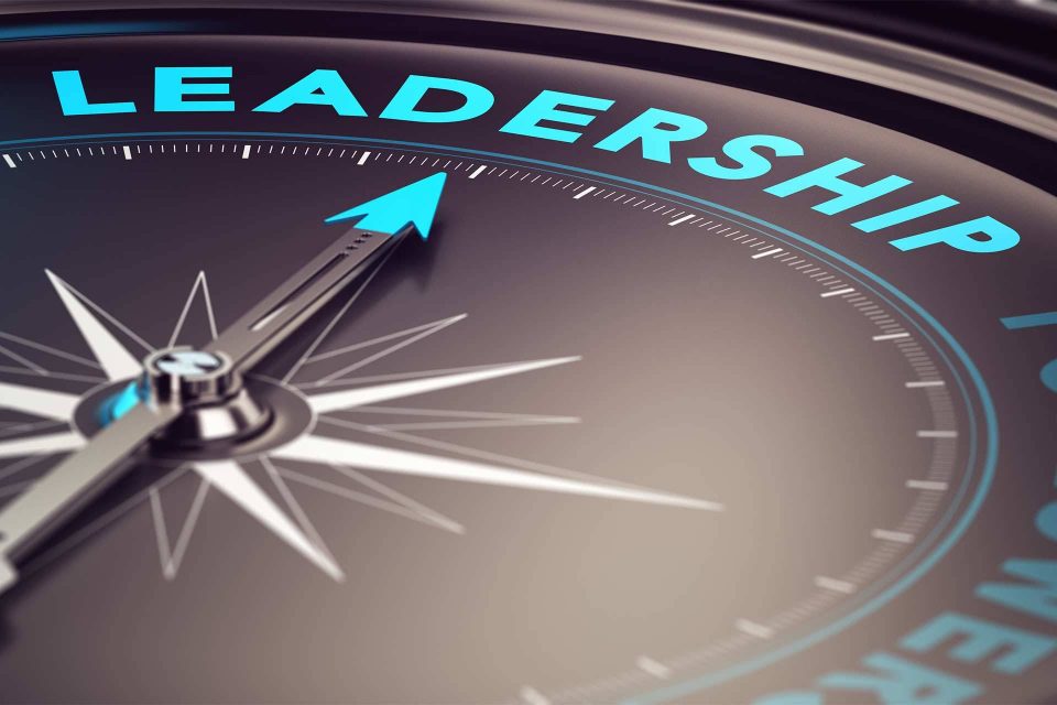 Black compass with aqua blue lettering that says Leadership