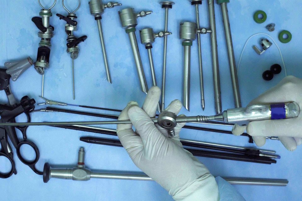 Hands covered in white latex gloves completing functional cycles as part of BoneSim's process of reprocessing reusable medical devices.